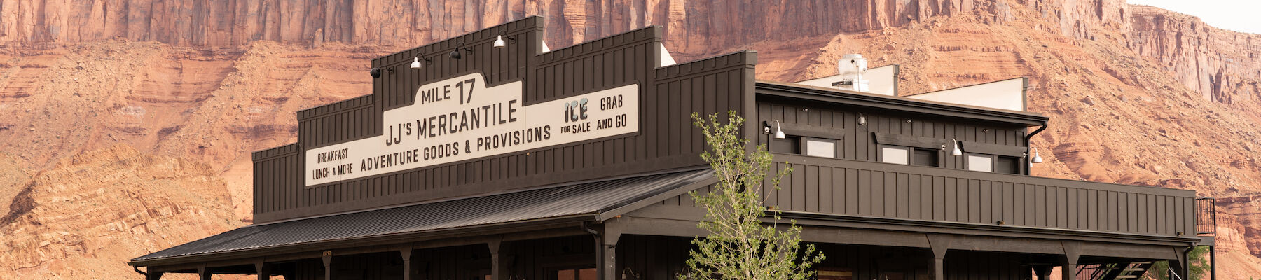 A modern building labeled "MILE 17 JJ'S MERCANTILE" offers adventure goods, with a red rock canyon backdrop.
