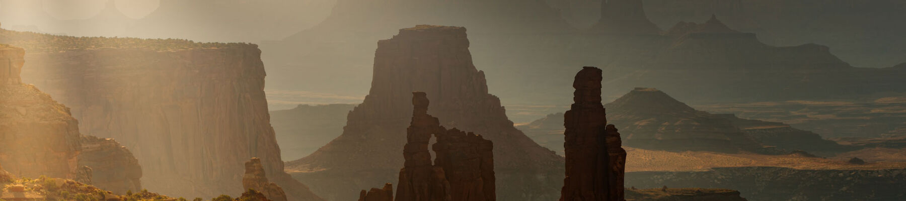 A stunning landscape of a canyon with dramatic rock formations, bathed in the soft morning sunlight filtering through the mist.