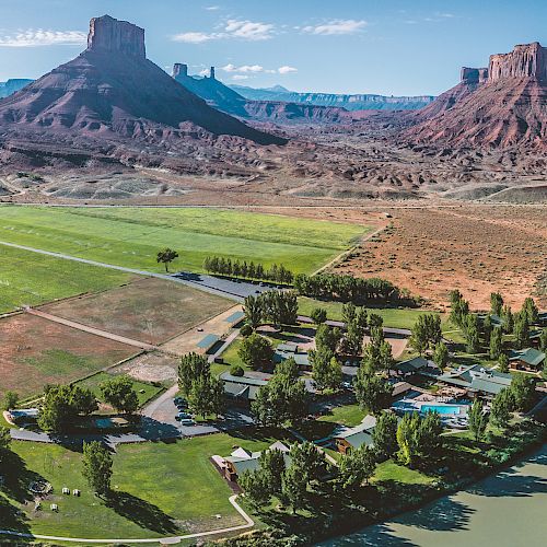 The image showcases a scenic landscape with a river, fields, trees, and several rock formations in the background.