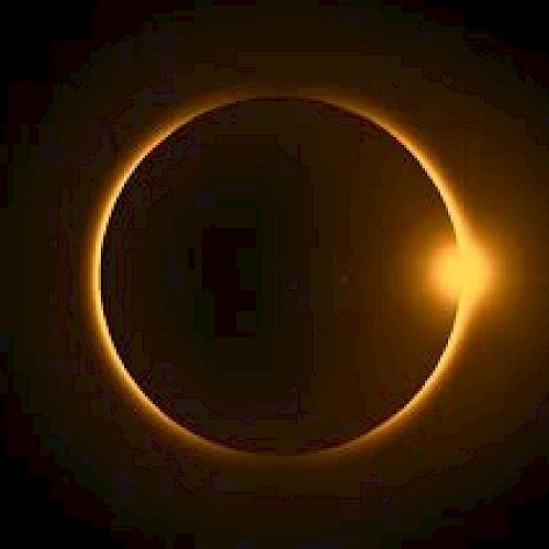 The image shows a solar eclipse with the Sun partially visible behind the Moon, creating a ring of light known as the "ring of fire."