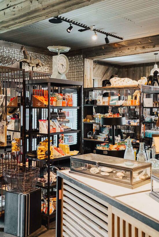 The image shows a store interior with shelves of various products, including packaged goods and decor items, under warm lighting.