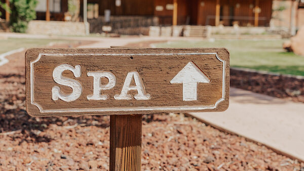 A wooden sign labeled "SPA" points forward, with a rustic building and trees in the background.