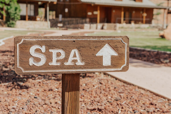 A wooden sign labeled "SPA" points forward, with a rustic building and trees in the background.