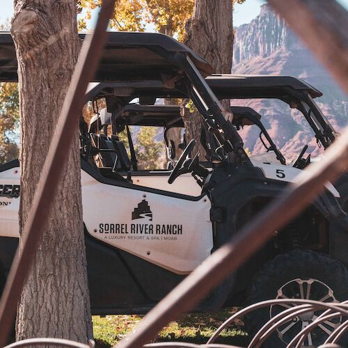 The image shows off-road vehicles next to trees with a mountain in the background, labeled "Sorrel River Ranch."