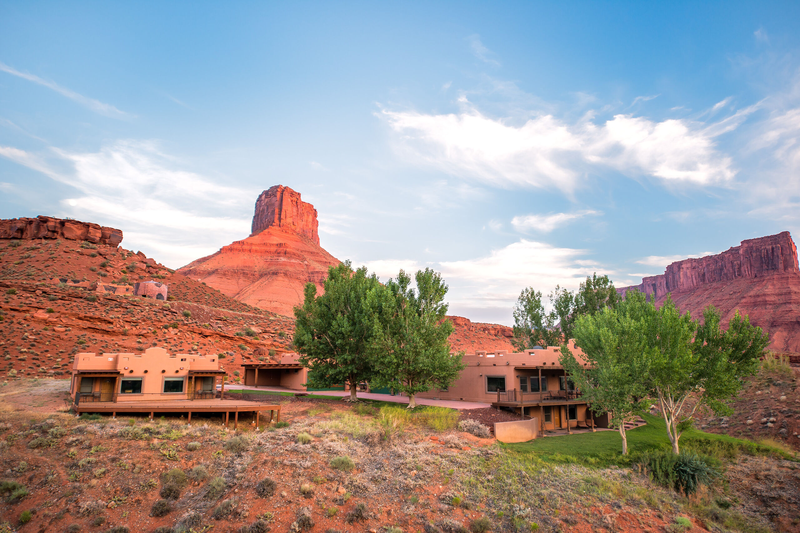 A wide exterior view of a building in the desert with a mountain in the background