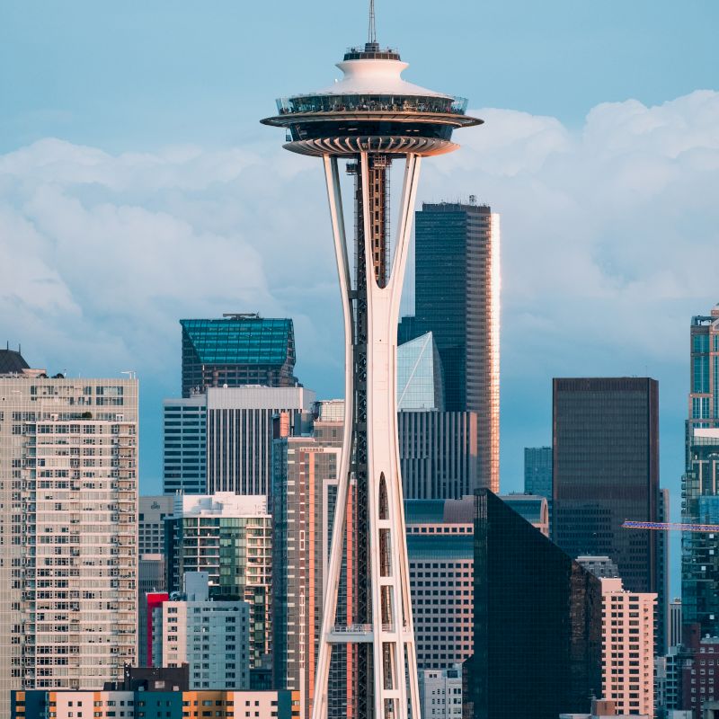 The image showcases the Space Needle standing prominently amid the cityscape of Seattle, with various buildings in the background.