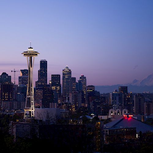 This image captures the Seattle skyline at dusk, featuring the Space Needle prominently, with Mount Rainier visible in the background.